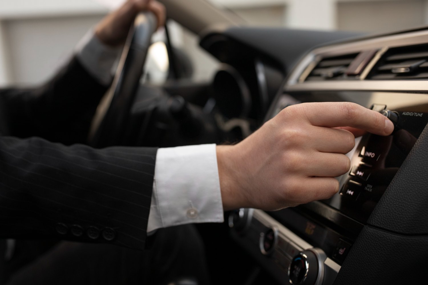 Professional chauffeur at the wheel adjusting controls — real flight tracking lets the driver adapt to delays